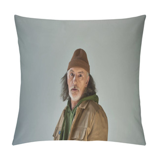 Personality  Thoughtful And Discouraged Hipster Style Senior Man In Beanie Hat And Brown Jacket Looking At Camera While Standing On Grey Background, Aging Population Lifestyle Concept Pillow Covers