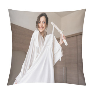 Personality  Happy Young Bride With Brunette Hair In White Silk Robe Holding Soft Hanger With Elegant Wedding Dress And Smiling In Bedroom Of Hotel Room, Special Occasion, Charming Woman  Pillow Covers