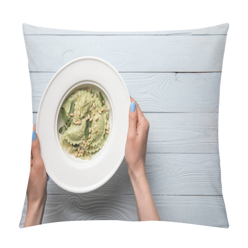 Personality  cropped view of woman holding plate with green ravioli with pine nuts and sage at wooden table pillow covers