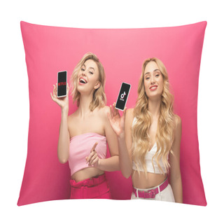 Personality  KYIV, UKRAINE - MARCH 10, 2020: Positive Blonde Friends Holding Smartphones With Netflix And TikTok Apps On Pink Background Pillow Covers