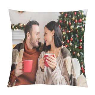 Personality  Joyful Couple With Cups Of Cocoa Sitting Under Warm Blanket And Smiling At Each Other Near Blurred Christmas Tree Pillow Covers