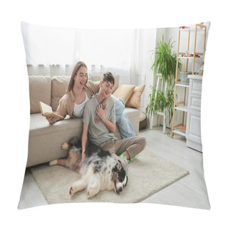 Personality  Cheerful Man Sitting On Carpet And Cuddling Australian Shepherd Dog And Touching Hand Of Gay Partner With Long Hair Holding Book In Modern Living Room  Pillow Covers