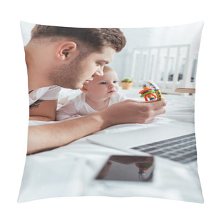 Personality  Young Father Showing Baby Rattle To Cute Son While Lying On Bed Near Gadgets Pillow Covers