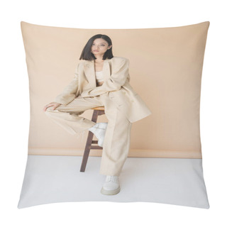 Personality  Brunette Asian Woman In Stylish Pantsuit And Boots Sitting On Stool On Beige Background Pillow Covers