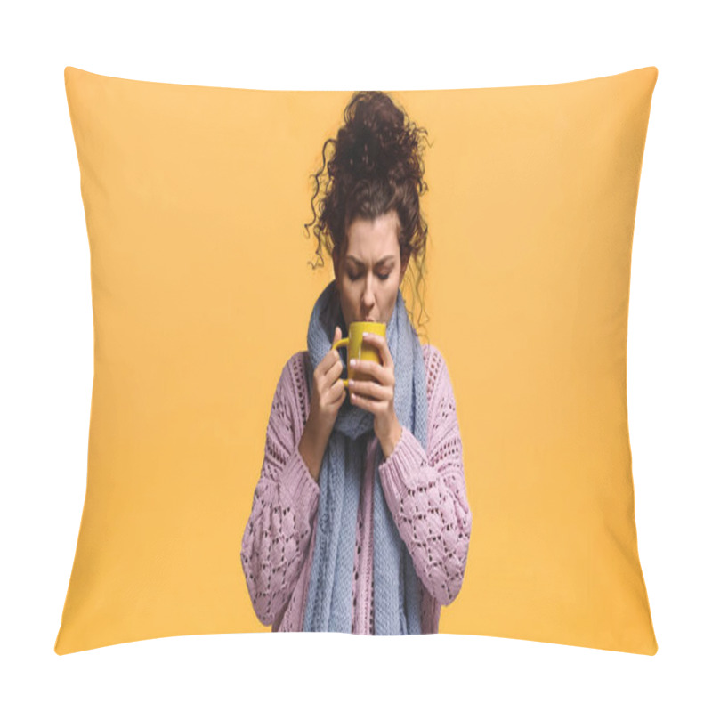 Personality  young woman in sweater and scarf drinking warm tea isolated on orange pillow covers