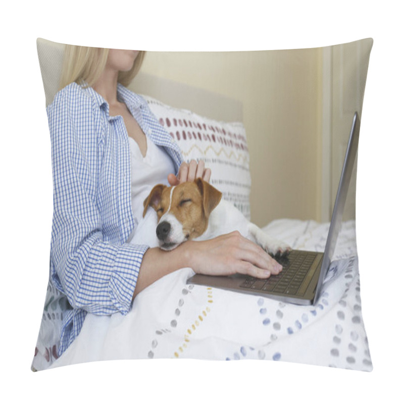 Personality  Close up shot of young woman working remotely from home in her bed on laptop due to coronavirus quarantine. Freelancer female with her jack russell terrier puppy. Copy space, background, pillow covers