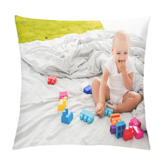 Personality  Funny Barefoot Baby In White Clothes Sitting On Bed Near Colorful Construction And Taking Fingers Into His Mouth Pillow Covers