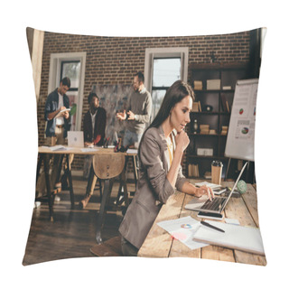 Personality  Pensive Business Woman Sitting At Desk With Laptop And Working On Project At Loft Office With Colleagues On Background Pillow Covers