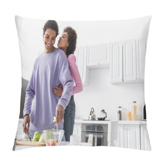 Personality  African American Woman Hugging And Pouting Lips Near Boyfriend Cooking Salad In Kitchen  Pillow Covers