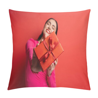 Personality  Happy Blurred Woman With Brunette Hair Smiling While Standing In Magenta Party Dress And Holding Wrapped Present With Ribbon For Holiday On Red Background  Pillow Covers