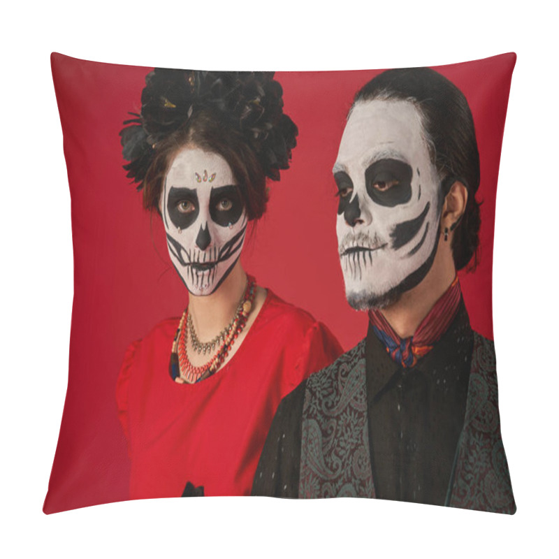 Personality  dia de los muertos couple, woman in skull makeup and black wreath looking at camera near man on red pillow covers