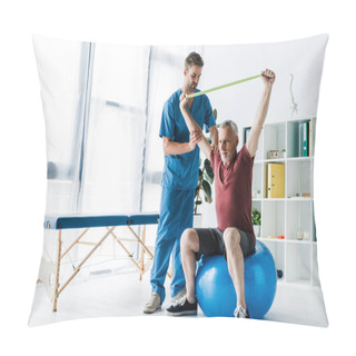 Personality  Doctor Standing Near Middle Aged Man Exercising With Resistance Band While Sitting On Fitness Ball  Pillow Covers