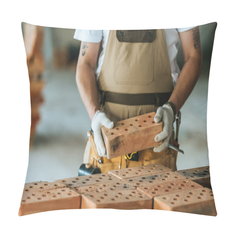Personality  cropped image of construction worker in protective gloves holding brick at construction site  pillow covers