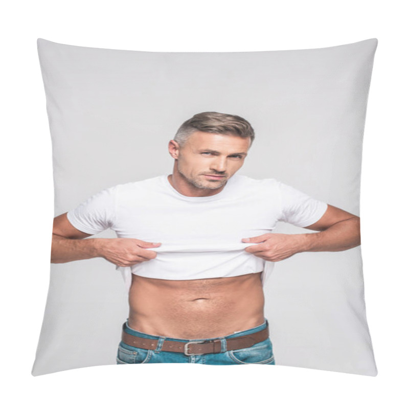 Personality  handsome man in jeans taking off white t-shirt and looking at camera isolated on grey pillow covers