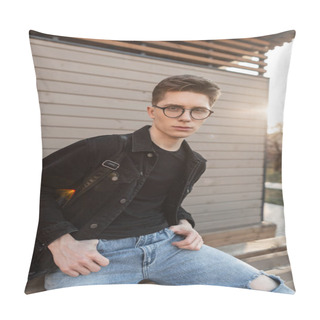 Personality  Confident Young Man Hipster In Fashionable Denim Clothing In Stylish Glasses Sits Near Wooden Building Outdoors. Trendy American Guy Rests On Background Bright Spring Sunset. Fashion Clothes For Men. Pillow Covers