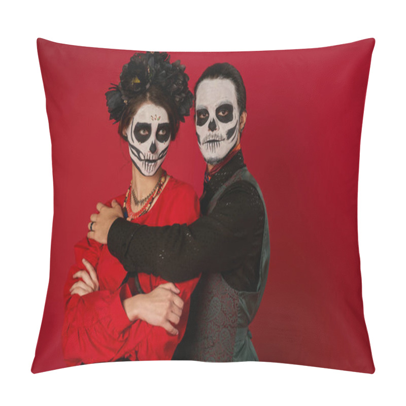 Personality  couple in dia de los muertos makeup, man embracing woman standing with folded arms on red pillow covers