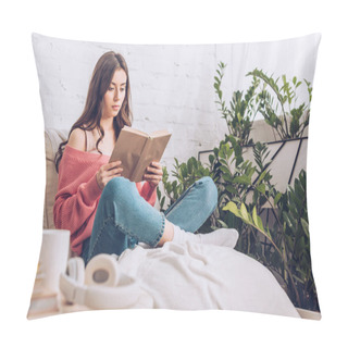 Personality  Selective Focus Of Focused Young Woman Reading Book While Sitting With Crossed Legs Near Green Plants At Home Pillow Covers