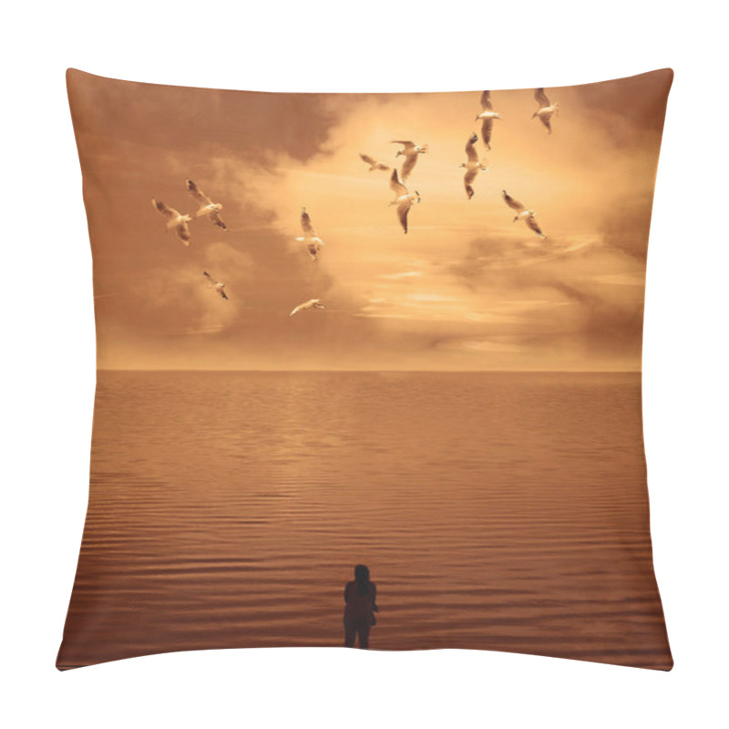 Personality  silhouette of woman standing near the water looking at the sunset across the lake. woman  enjoying view of rising sun in early  morning. a flock of seagulls are flying in the sky overhead pillow covers