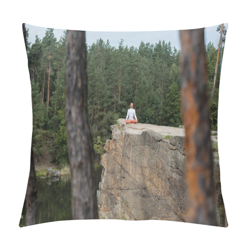 Personality  buddhist meditating in lotus pose on rocky cliff over river, blurred foreground pillow covers