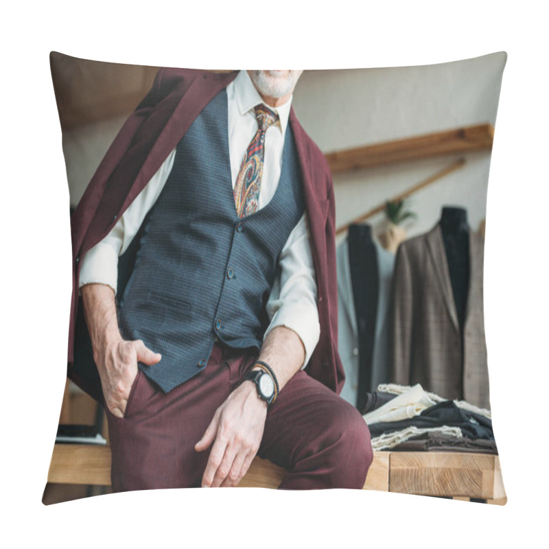 Personality  cropped shot of mature man with jacket on shoulders sitting on table pillow covers