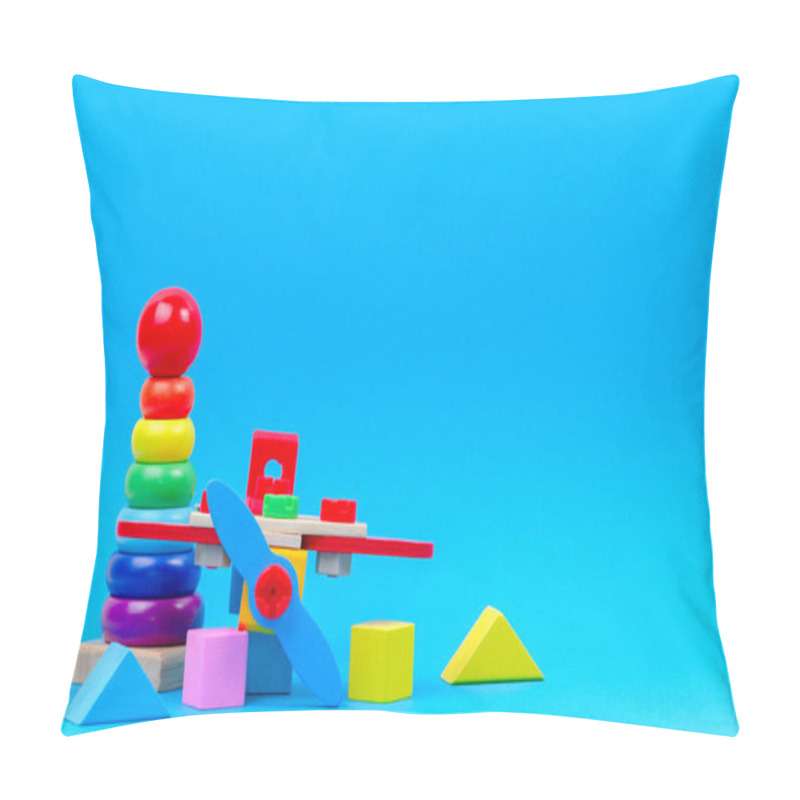 Personality  Baby kid toy background. Wooden toy plane, baby stacking rings pyramid and colorful blocks on blue background pillow covers