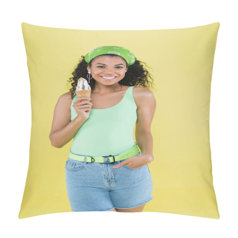 Personality  happy african american woman in green kerchief holding ice cream and standing with hand in pocket isolated on yellow pillow covers