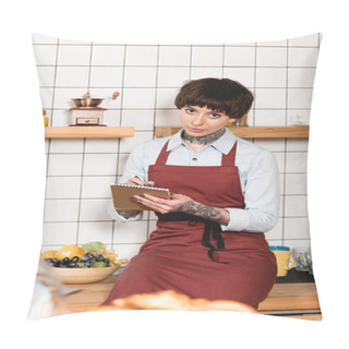 Personality  Selective Focus Of Pretty Barista In Apron Writing In Notebook And Looking At Camera Pillow Covers