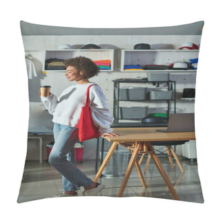 Personality  Side View Of Young And Positive African American Craftswoman With Shoulder Bag Holding Coffee To Go And Standing Near Laptop On Table In Print Studio, Enthusiastic Business Owner Working In Workshop Pillow Covers