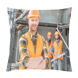 Personality  Smiling Builder Standing At Construction Site With Crossed Arms While His Colleagues Standing Blurred On Background Pillow Covers