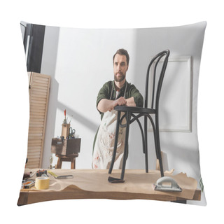 Personality  Bearded Restorer In Apron Looking At Camera Near Wooden Chair In Workshop  Pillow Covers