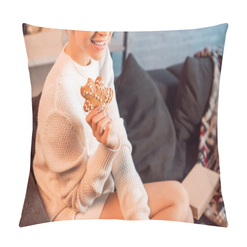 Personality  cropped view of young woman sitting on couch, posing and holding gingerbread cookie at christmas time pillow covers