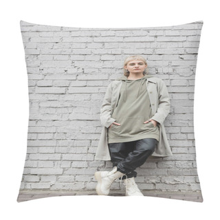 Personality  Young Woman With Makeup, Blonde Hair, Bangs, In Stylish Outfit, Long Hoodie, Coat, Black Leather Pants And Beige Boots Standing With Hands In Pockets Near Grey Brick Wall And Looking At Camera  Pillow Covers