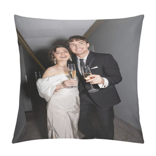 Personality  Joyful Groom Hugging Young And Brunette Bride In White Wedding Dress And Holding Glasses Of Champagne While Standing And Smiling Together In Hallway Of Hotel  Pillow Covers