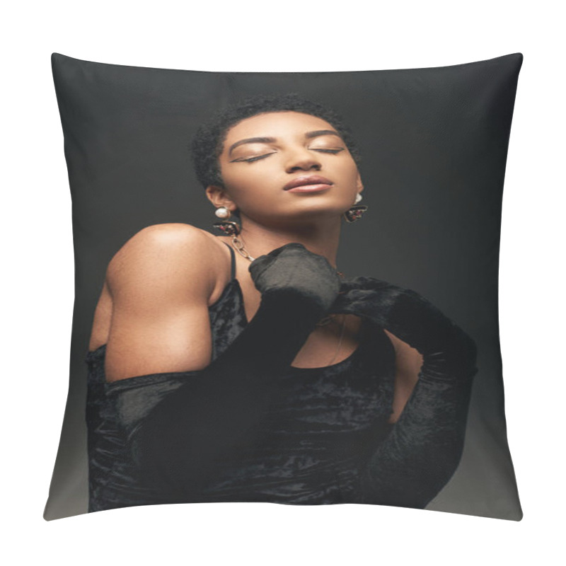 Personality  Portrait of fashionable and elegant short haired african american woman with makeup, golden accessories and gloves standing with closed eyes isolated on black, high fashion and evening look pillow covers