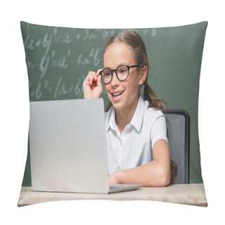 Personality  Positive Schoolkid Adjusting Eyeglasses Near Laptop And Chalkboard On Blurred Background Pillow Covers