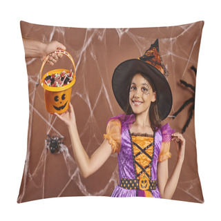 Personality  Happy Girl In Witch Hat And Halloween Costume Looking At Camera Near Hand Holding Sweets In Bucket Pillow Covers