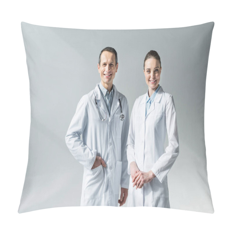 Personality  smiling adult doctors looking at camera on grey pillow covers