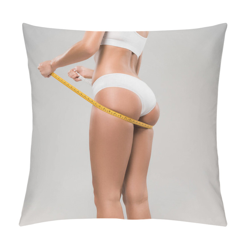 Personality  cropped view of slim woman in underwear holding measuring tape under buttocks isolated on grey pillow covers