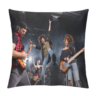 Personality  KYIV, UKRAINE - AUGUST 25, 2020: Vocalist With Microphone Screaming While Jumping Up Near Guitarists With Backlit And Female Drummer On Background Pillow Covers