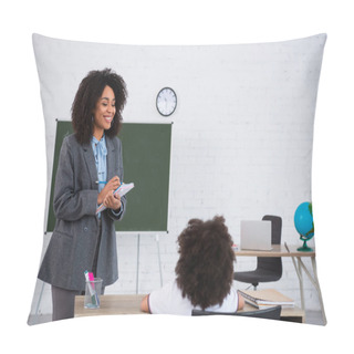 Personality  Positive African American Teacher Writing On Notebook Near Blurred Schoolkid During Lesson  Pillow Covers