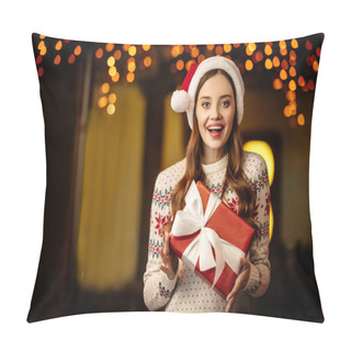 Personality  Amazed Young Woman In Warm Sweater And Santa Hat Holding Gift Box And Looking At Camera Pillow Covers
