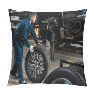 Personality  Young Mechanic Holding Car Wheel Near Raised Car In Workshop Pillow Covers