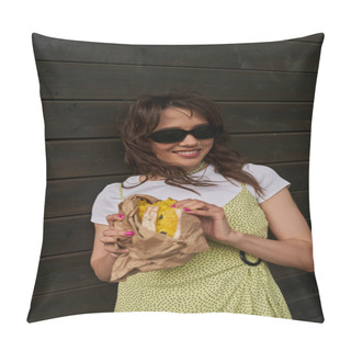 Personality  Brunette And Stylish Woman In Sunglasses And Summer Outfit Smiling While Holding Fresh Bun In Craft Package And Standing Near Wooden House At Background, Summer Vibes Concept, Tranquility Pillow Covers
