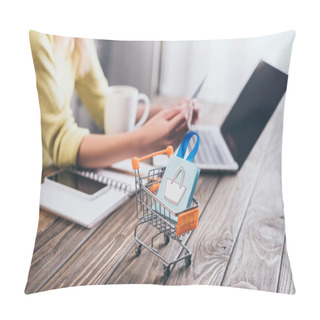 Personality  Selective Focus Of Small Shopping Bag In Shopping Trolley With Woman Using Laptop On Background Pillow Covers