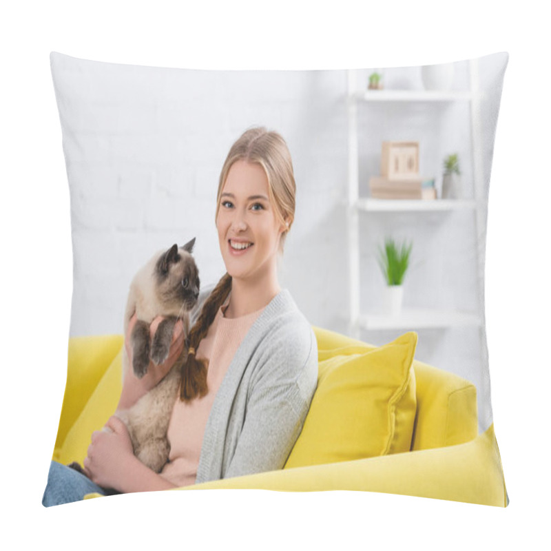 Personality  Happy woman holding furry siamese cat and looking at camera on yellow couch  pillow covers