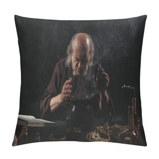 Personality  Alchemist In Dark Robe Looking Into Steaming Pot Near Herbal Ingredients On Black Background  Pillow Covers
