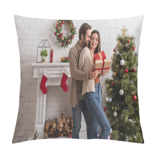 Personality  Man Embracing Happy Wife Holding Presents Near Christmas Tree And Decorated Fireplace Pillow Covers