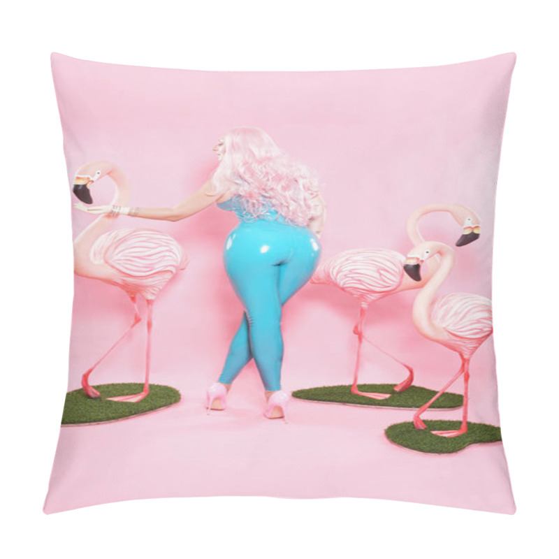 Personality  cute plump girl dressed in a shiny blue latex swimsuit posing with a big Flamingo on a pink studio background pillow covers