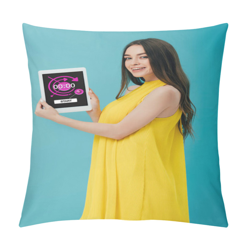 Personality  beautiful brunette girl in yellow dress showing digital tablet with stopwatch app isolated on turquoise pillow covers