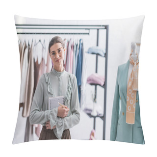Personality  Designer With Notebook Looking At Camera Near Mannequin With Jacket  Pillow Covers